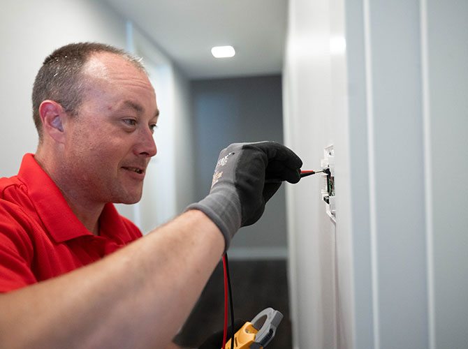 THERMOSTAT-2-670×500 Age technician installing a thermostat on the wall